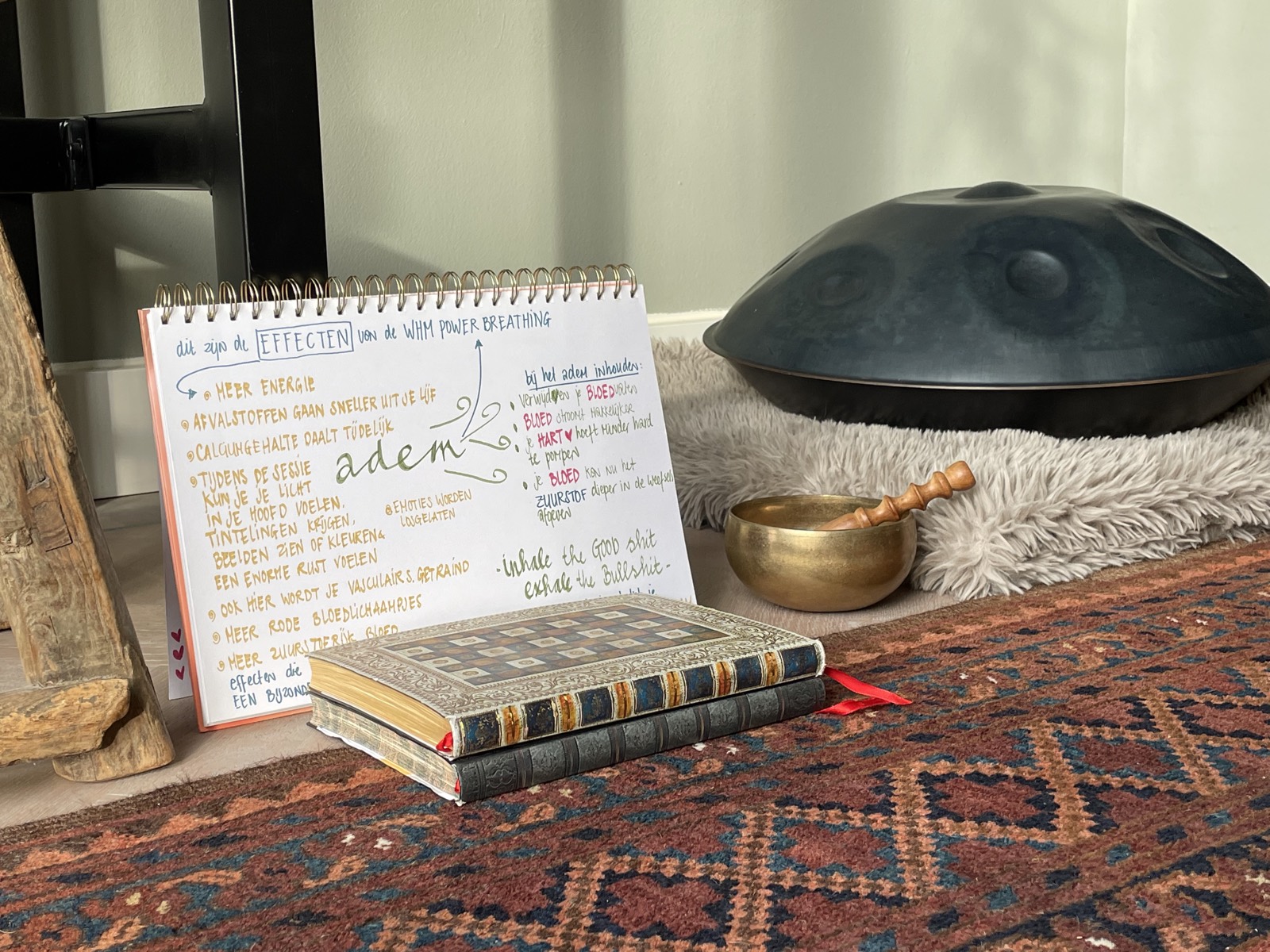 De ademruimte in Den Haag: een schrift met aantekeningen over ademhaling, een handpan en een klankschaal op een kleed.