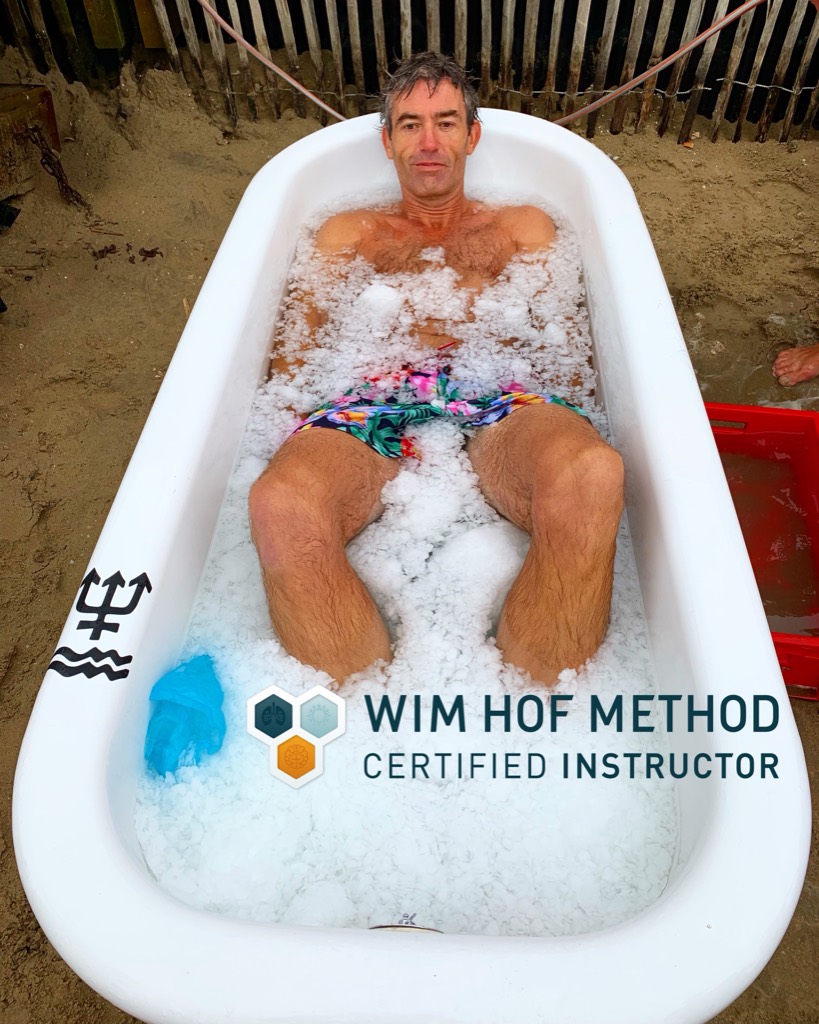 Jeroen in een met ijs gevulde badkuip op het strand, met het keurmerk Wim Hof Method Certified Instructor.