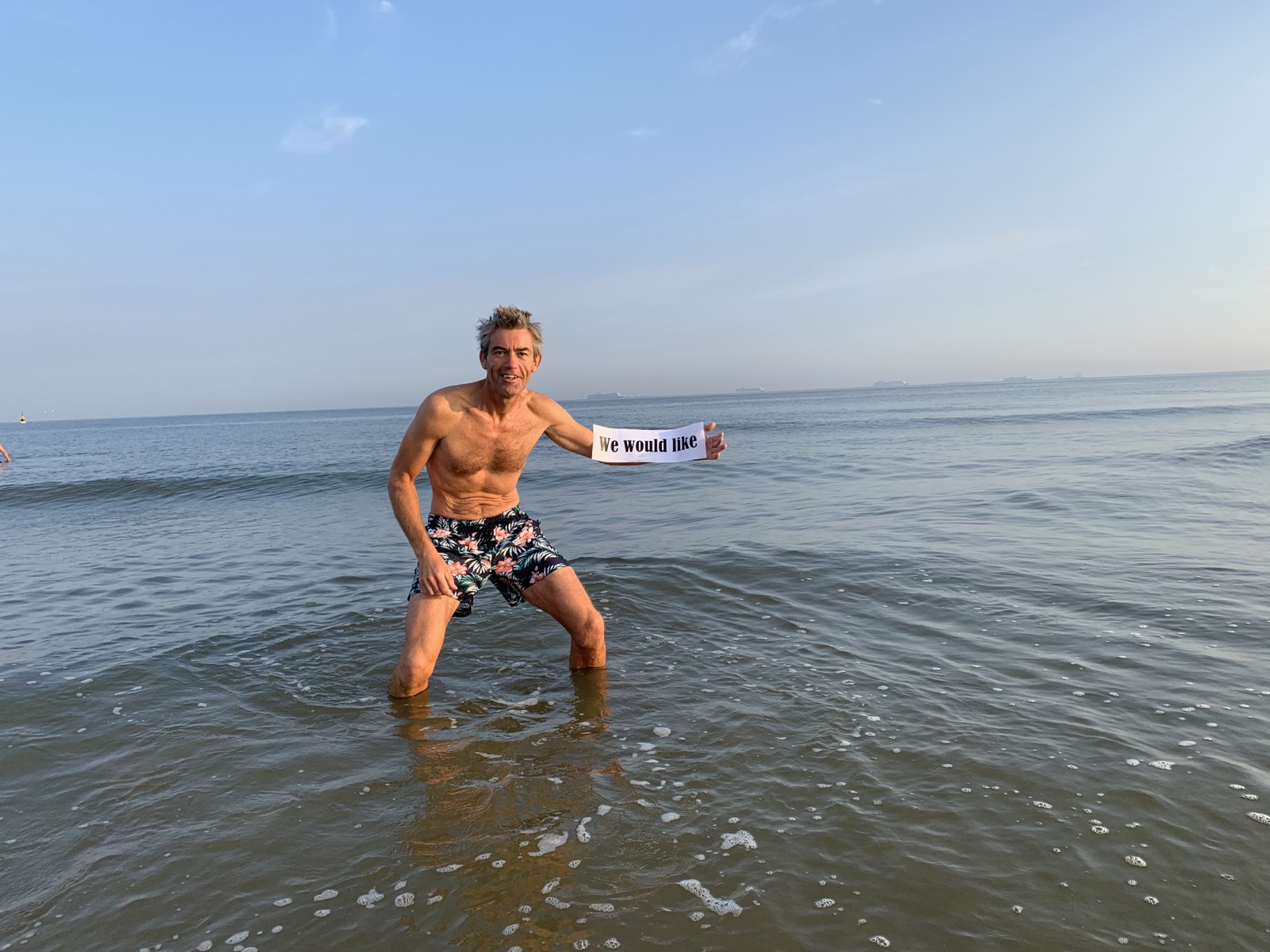 Jeroen staat in de branding van de Noordzee bij Scheveningen.